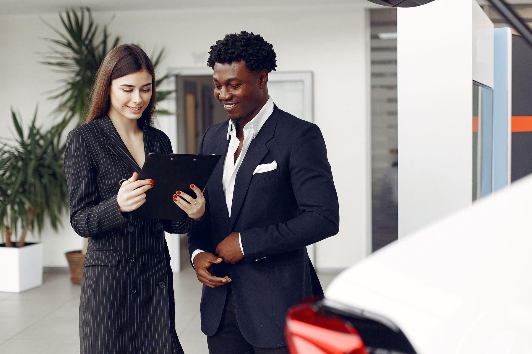Business professionals reviewing a document in a vehicle showroom